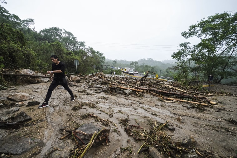 Image: A man crosses a highway blocked by a landslide triggered by Hurricane Otis
