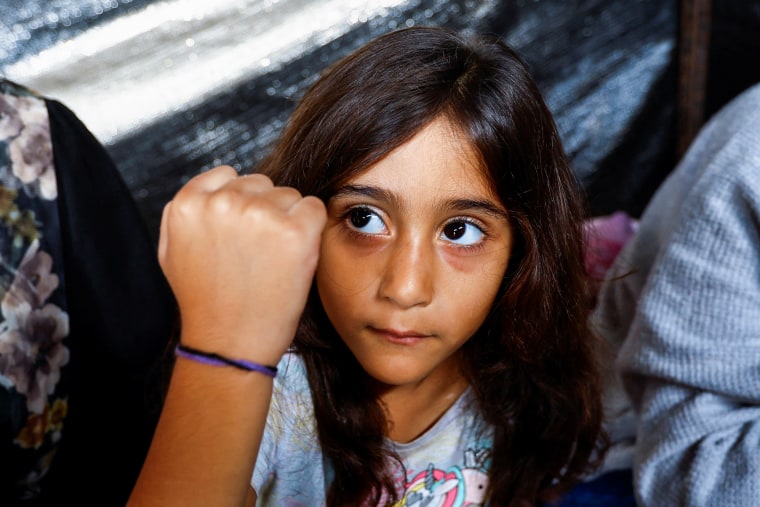 The daughter of Ali Daba holds up her bracelet at their shelter in Khan Younis, Gaza.