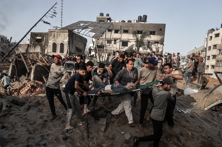 Injured Palestinians are taken away from destroyed buildings after Israeli airstrikes and artillery fires continue in Gaza on Oct. 25, 2023. 