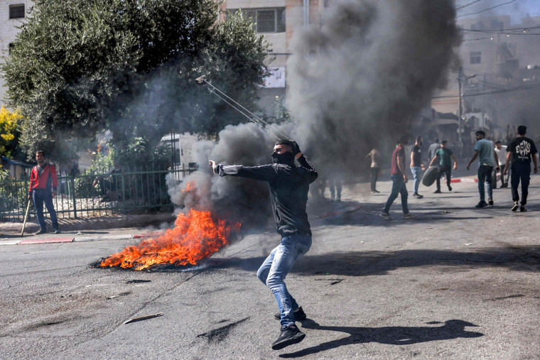 A Palestinian protester hurls back a tear gas canister with a sling during clashes with Israeli forces following a rally in solidarity with Gaza in Hebron in the occupied West Bank on Oct. 13, 2023.