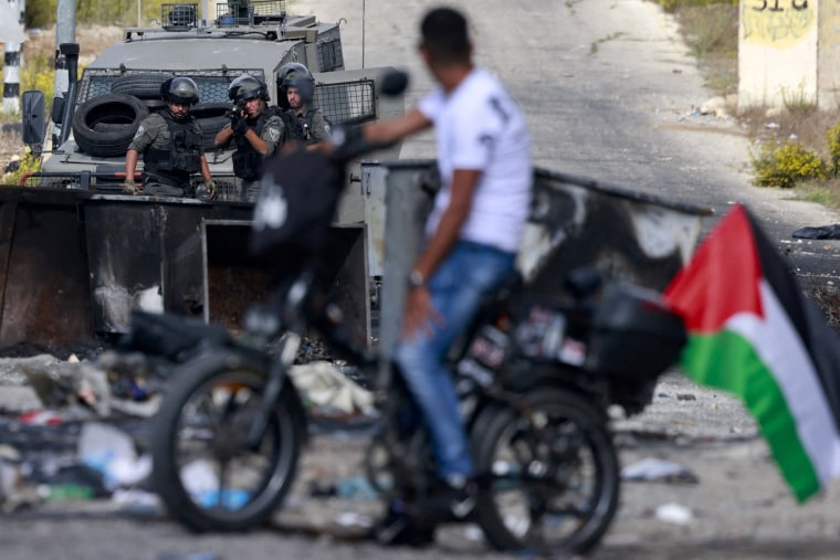 A Palestinian man faces Israeli troops during clashes in Ramallah near the Israeli settlement of Beit El on Oct. 20, 2023.