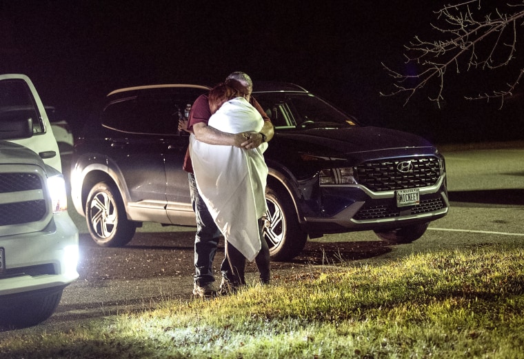 Image: A woman is hugged by a man at a reunification center at Auburn Middle School