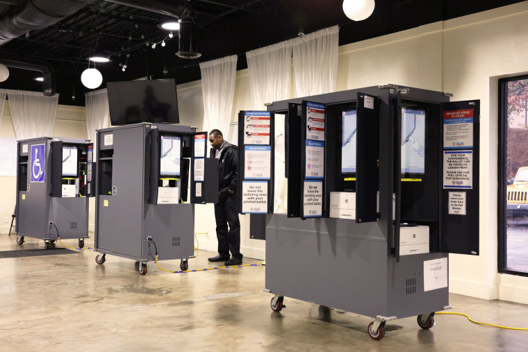 A man stands among voting machines while casting his ballot