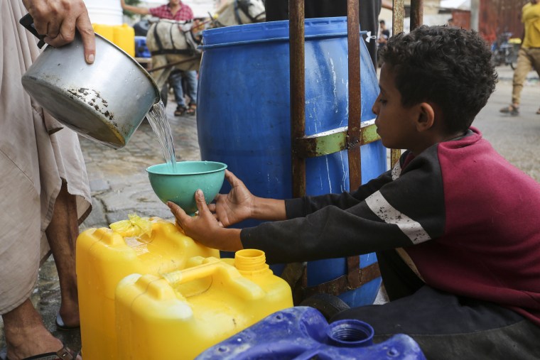A Palestinian fills a cup with drinking water in Rafah, Gaza.