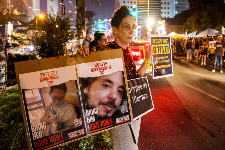 A woman stands with a sign with photos of two of the hostages held by Palestinian militants during a demonstration