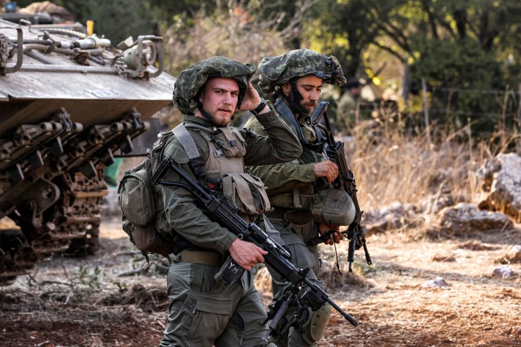 Israeli army soldiers stand by a tracked vehicle