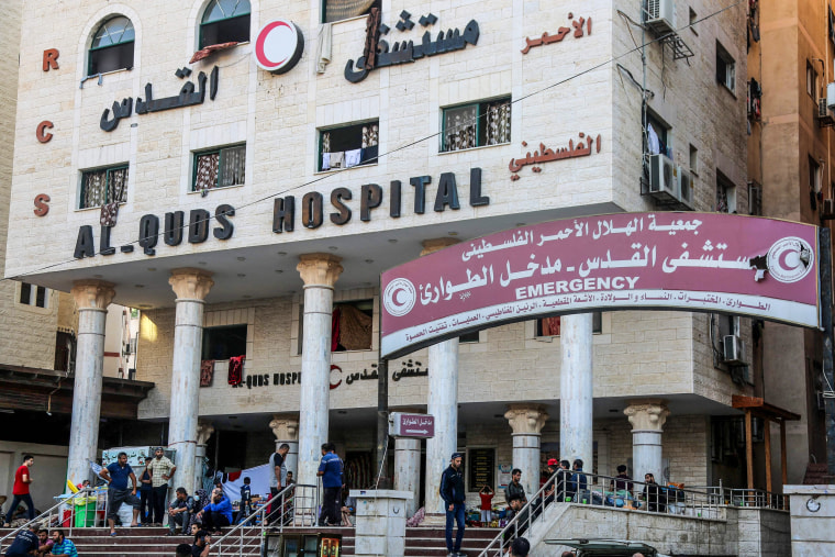 Image: People wait outside Gaza City's Al-Quds Hospital