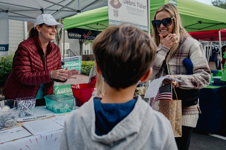 Debra Tisler, left, chats with a mother at her booth at the Clifton Day Festival in Clifton, Va., on Oct. 8, 2023. 