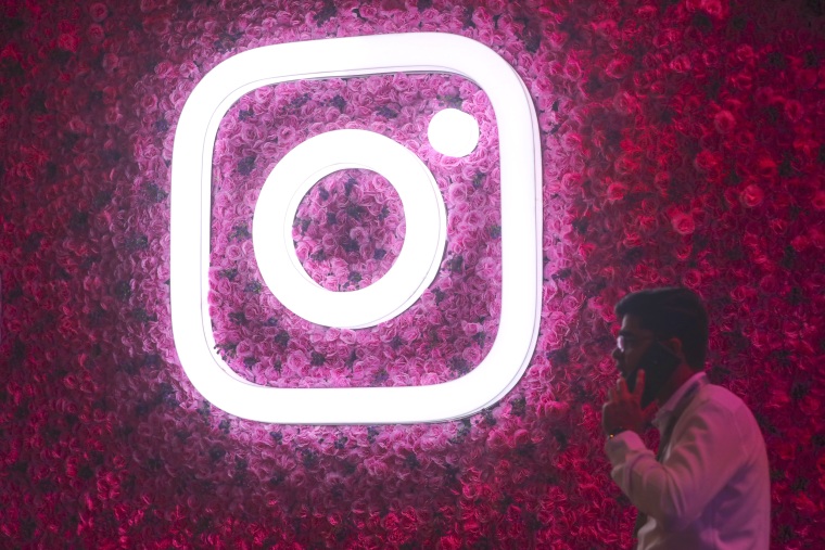 A man wlks by the Instagram logo, during a Meta event in Mumbai