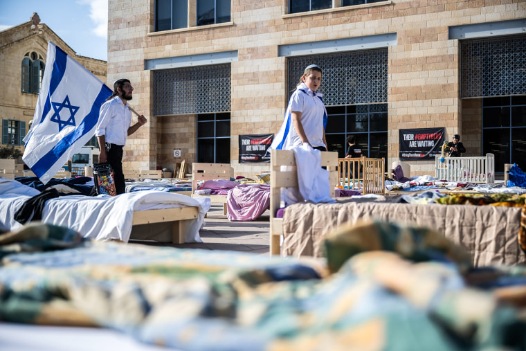 Image: People wearing Israeli flags visit The Empty Beds Installation 