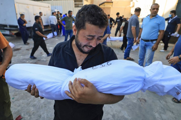 A Palestinian man holds the body of a relative during a funeral service in Deir Al-Balah, Gaza, on Oct. 31, 2023.