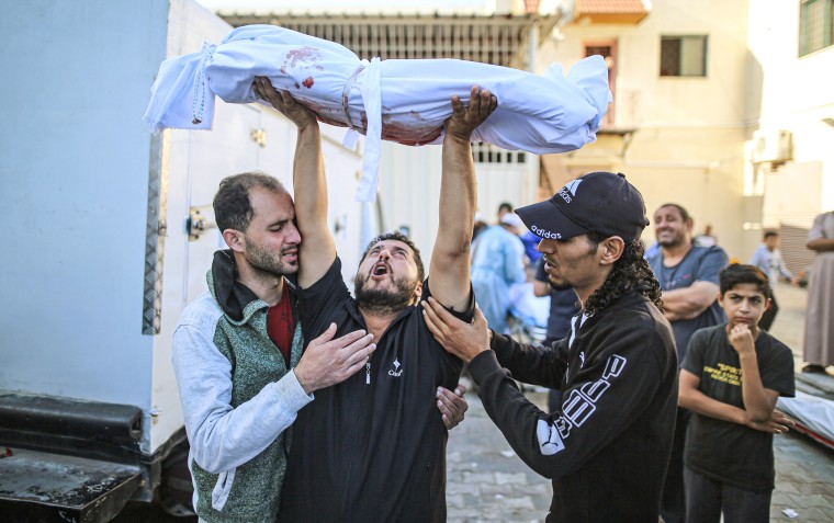 A mourner holds up the body of a relative as it is transported for burial at Al Aqsa Martyrs Hospital in Deir Al-Balah, Gaza, on Oct. 31, 2023. 