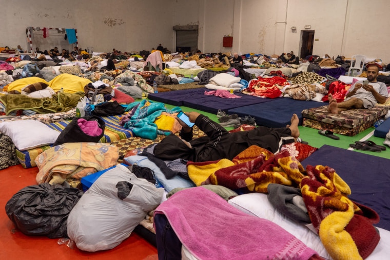 Gaza day laborers stranded in the West Bank sleep in a sports hall and check their phones for messages from their families.