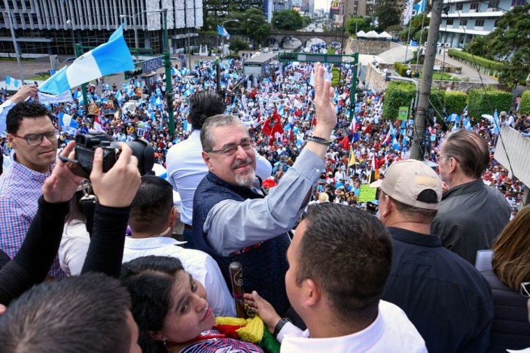 Desde un balcón, el presidente electo de Guatemala, Bernardo Arévalo, saluda a cientos de personas reunidas y ondeando banderas del país centroamericano. Fue el 20 de octubre de 2023, al conmemorarse el 79° aniversario de la llamada Revolución de octubre, cuando Guatemala tuvo sus primeras elecciones democráticas después de la dictadura de Jorge Ubico