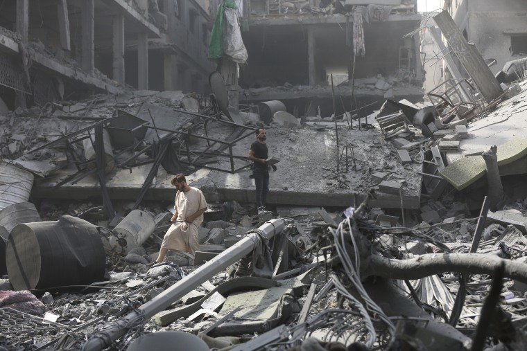 Palestinos inspeccionan los daños de edificios destruidos tras los ataques aéreos israelíes sobre Ciudad de Gaza, el lunes 23 de octubre de 2023. 