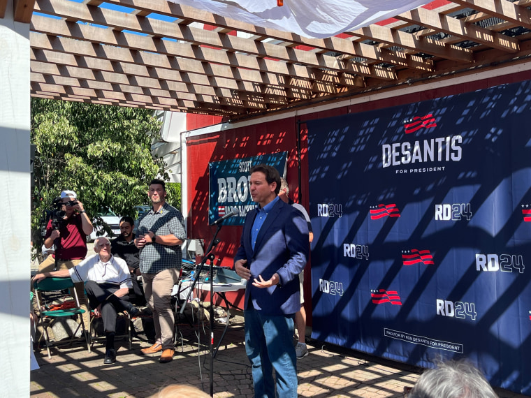 Ron DeSantis speaks at an event put on by his presidential campaign, with official campaign logos behind him.