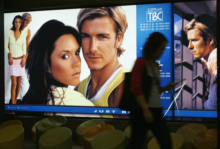 Pedestrians pass by an advertisement featuring soccer star and England Team captain David Beckham with his wife Victoria  June 19, 2003 in Tokyo, Japan.