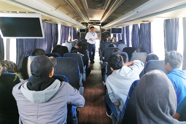 Migrant children and teenagers sit on a charter bus as a member of the Guatemalan Institute of Migration speaks