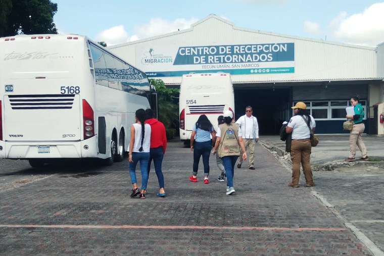 Migrant children and teenagers sit on a charter bus as a member of the Guatemalan Institute of Migration speaks