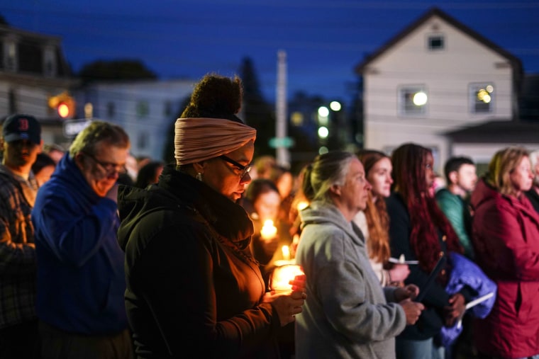 People hold candles while gathering outside for a vigil