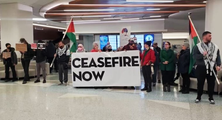 Protesters hold a sign that reads "Ceasefire Now."