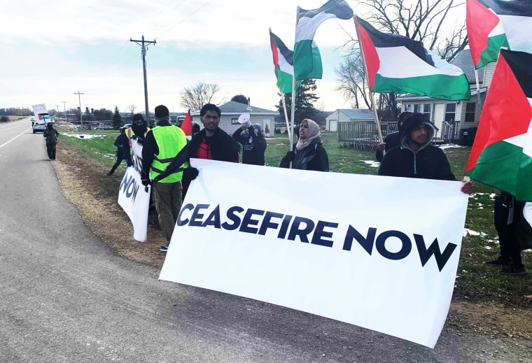 Protesters hold a sign that reads "Ceasefire Now."