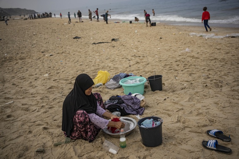A woman washes clothes with seawater at the beach in Deir al Balah, Gaza.