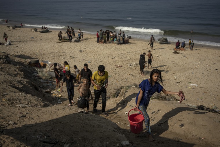 People carry seawater home from the beach in Deir al Balah, Gaza.