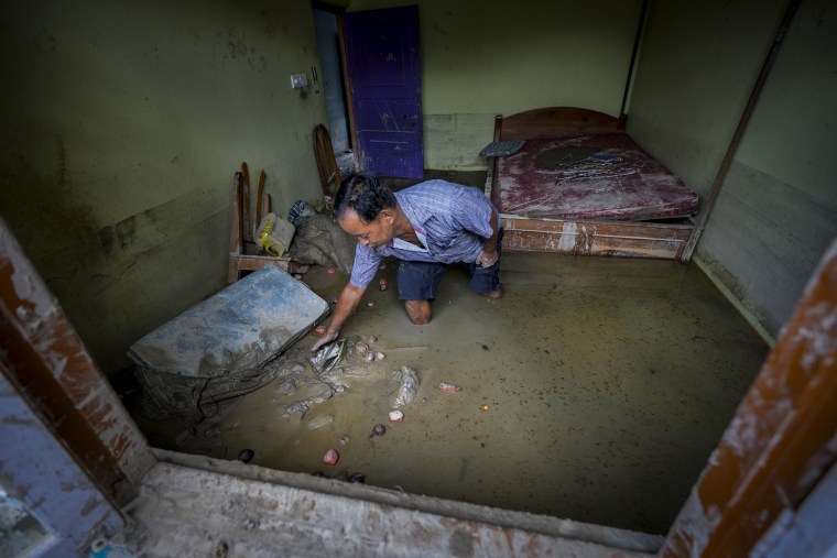A man searches for documents in his home during a flood in Sikkim, India.