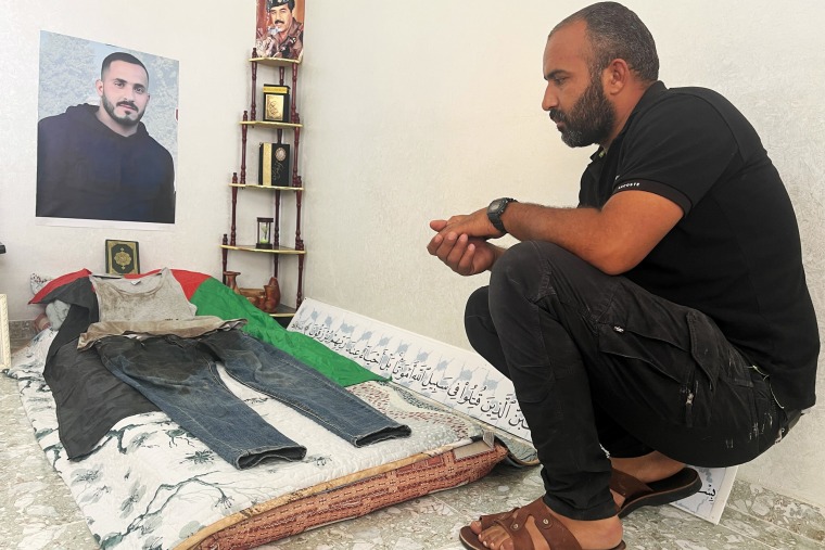 Murad Jebril kneels next to a shrine for his slain brother, Eisa, at the family home.