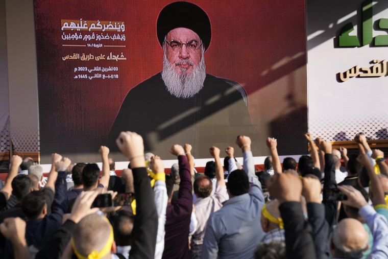Supporters of the Iranian-backed Hezbollah group raise their fists and cheer as Hezbollah leader Sayyed Hassan Nasrallah appears via a video link in Beirut on Nov. 3, 2023.
