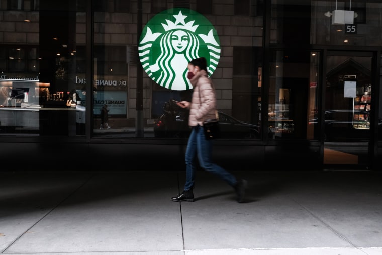 A woman walks by a Starbucks coffee shop in Manhattan, N.Y.
