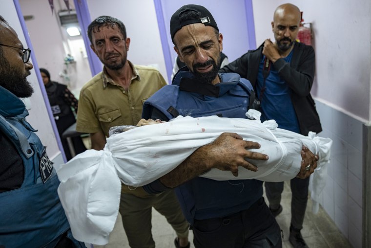Palestinian journalist Mohammed al-Aloul carries the body of his child killed in Deir al-Balah.