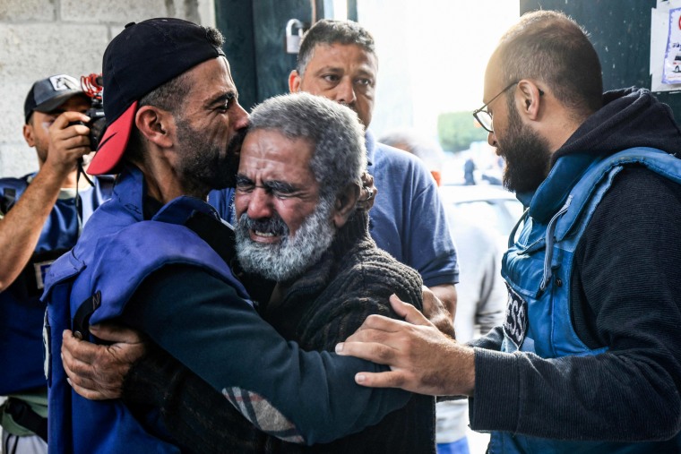 Palestinian cameraman Mohammed Alaloul, left, hugs his father after two of his children and his brother were killed in an Israeli strike on the Al-Maghazi refugee camp in Deir al-Balah.