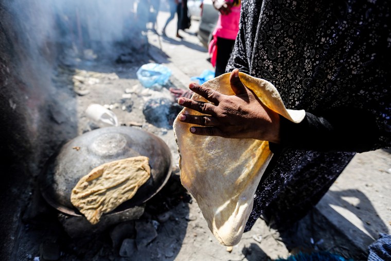 A woman makes bread over a fire in Khan Yunis, Gaza.