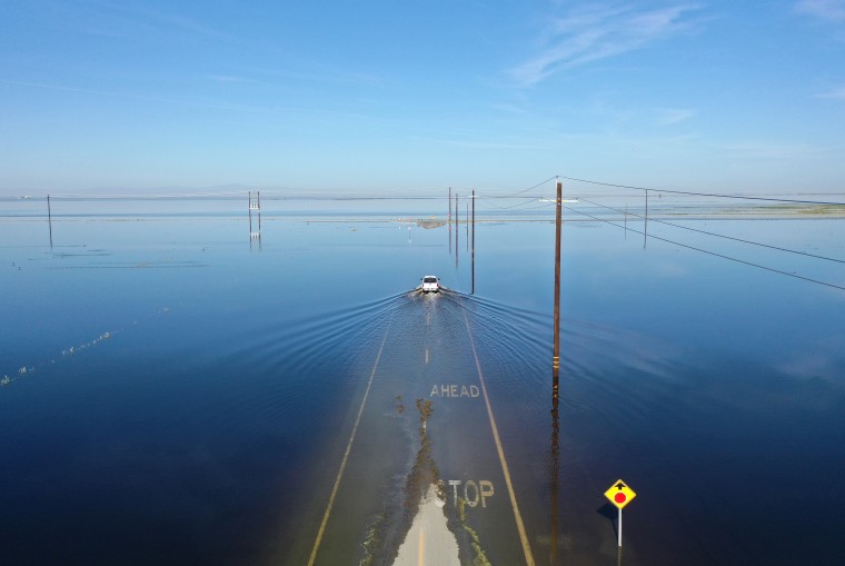 A vehicle drives through floodwaters near Corcoran, Calif