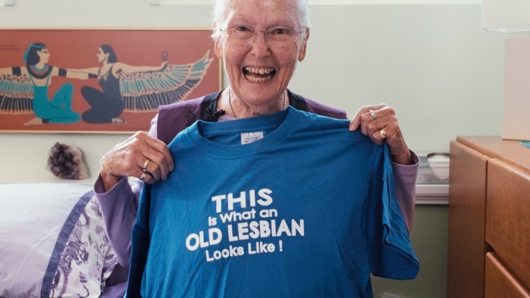 Edie Daly holds a blue t-shirt that says "This is what an old lesbian looks like!"