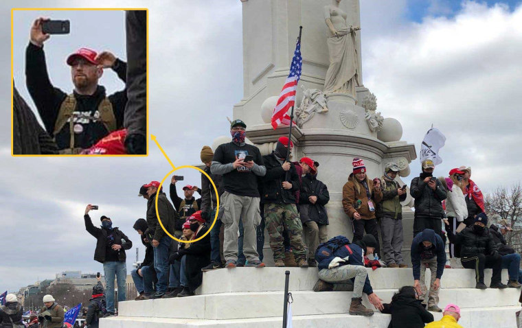 Edward Kelley at the Peace Monument across from the United States Capitol Building using a cell phone and wearing a red MAGA on Jan. 6, 2021.