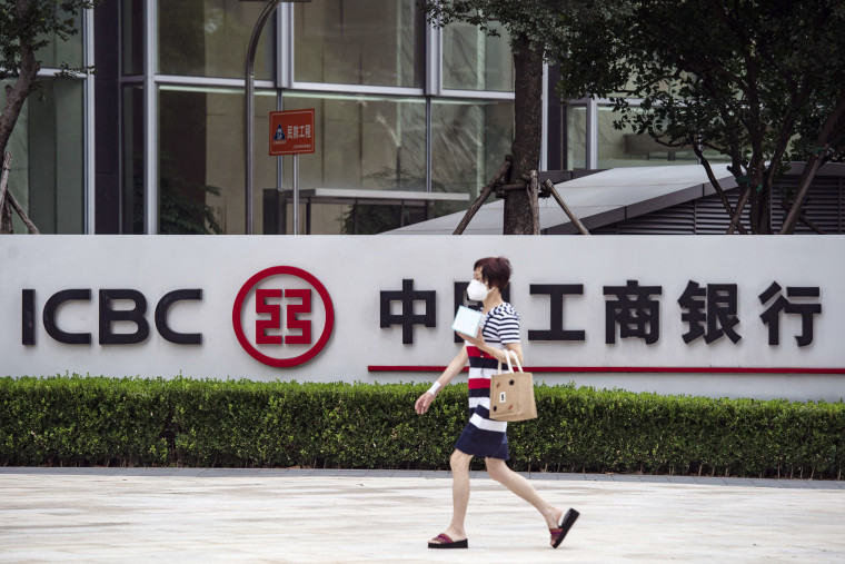 A woman walks by signage outside an Industrial and Commercial Bank of China Ltd. (ICBC) branch in Shanghai, China