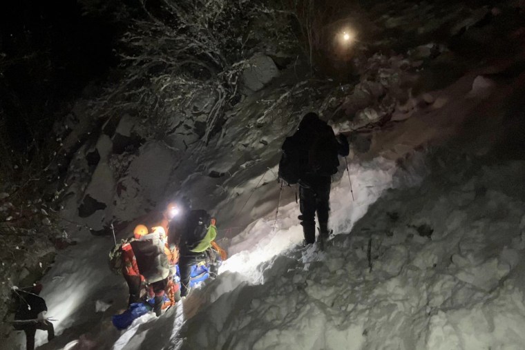 A search and rescue team descends with a distressed hiker.