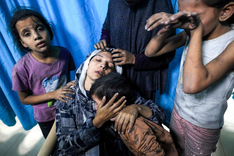 A wounded woman is surrounded by her children upon their arrival at Nasser Hospital after an airstrike hit their building in Khan Younis, Gaza.