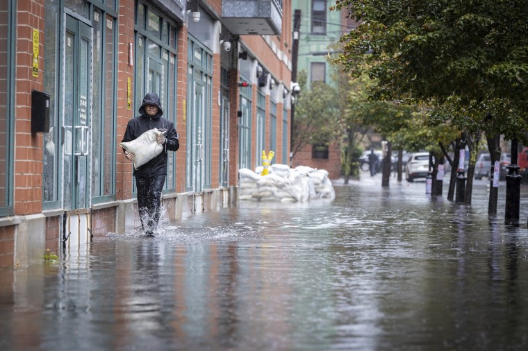 A person carries sands bags through floodwaters in Hoboken, N.J., on Sept. 29, 2023. 