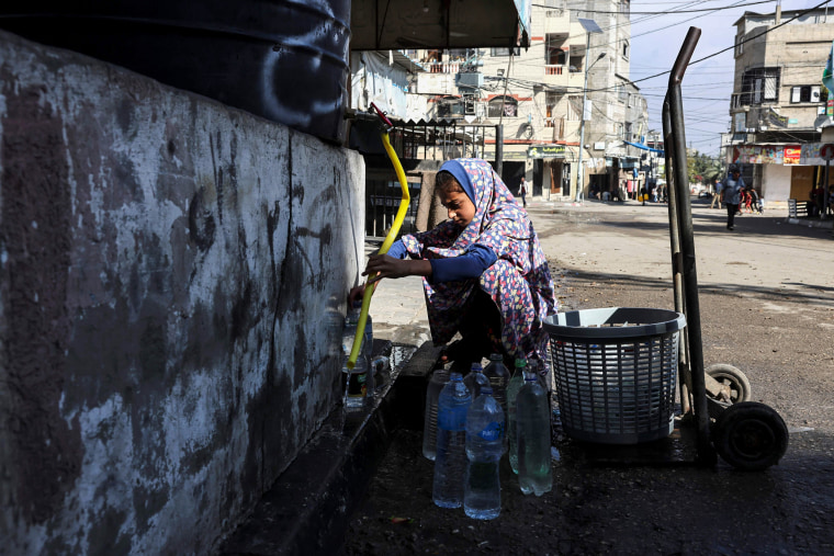 A girl fills bottles with water in Bureij, central Gaza.
