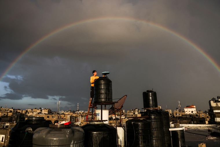 A man checks a water tank on the roof of a building in Rafah.