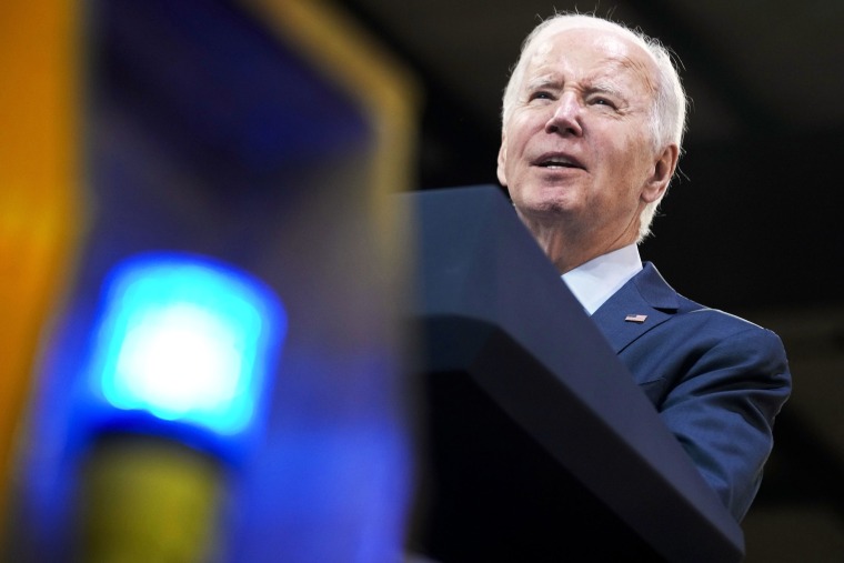 President Joe Biden speaks at podium at the Amtrak bear maintenance facility.