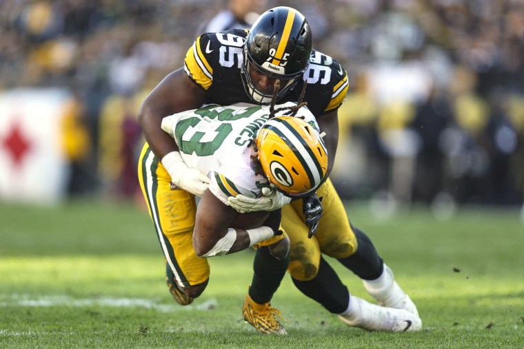 A Steelers football player tackles a Green Bay Packers playeer on the football field