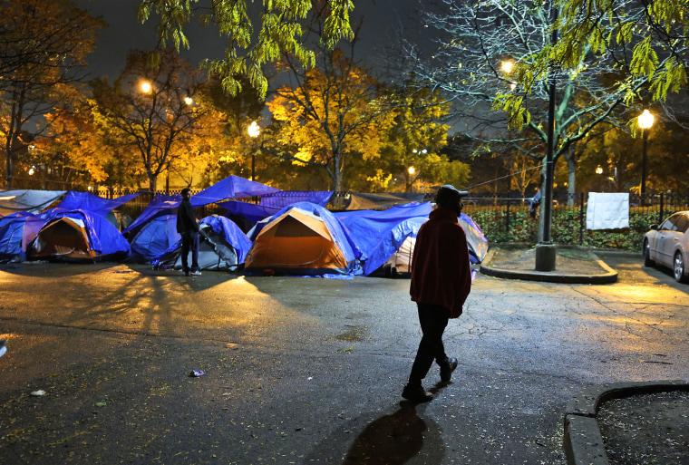 Nathan McCarthy walks through a parking lot outside the 15th District police station, a space he shares with newly arrived migrants in Chicago's Austin neighborhood on Nov. 5, 2023.