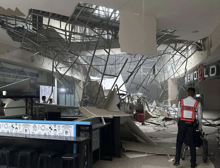 A security guard walks beside the damaged ceiling of a shopping mall in General Santos City, Philippines,