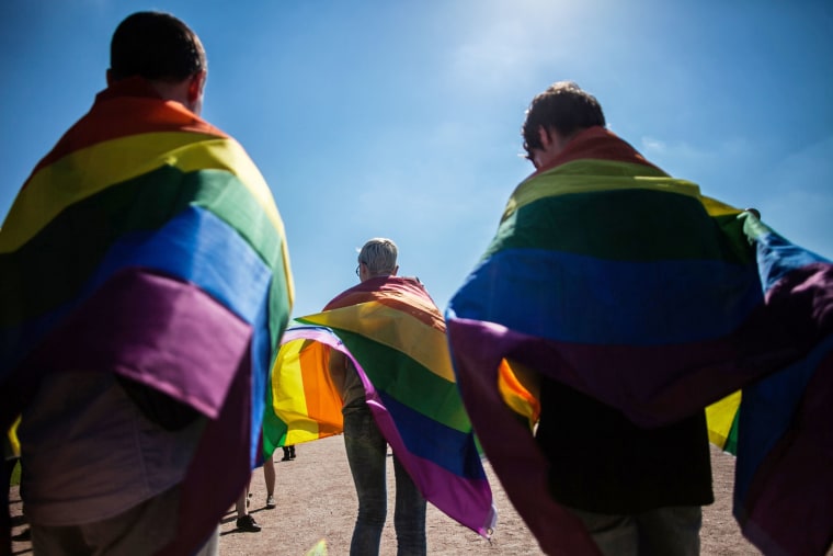 Activists walk with rainbow flags around their shoulders