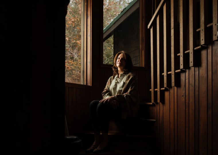 Linda Clary sits on the stairs in her home